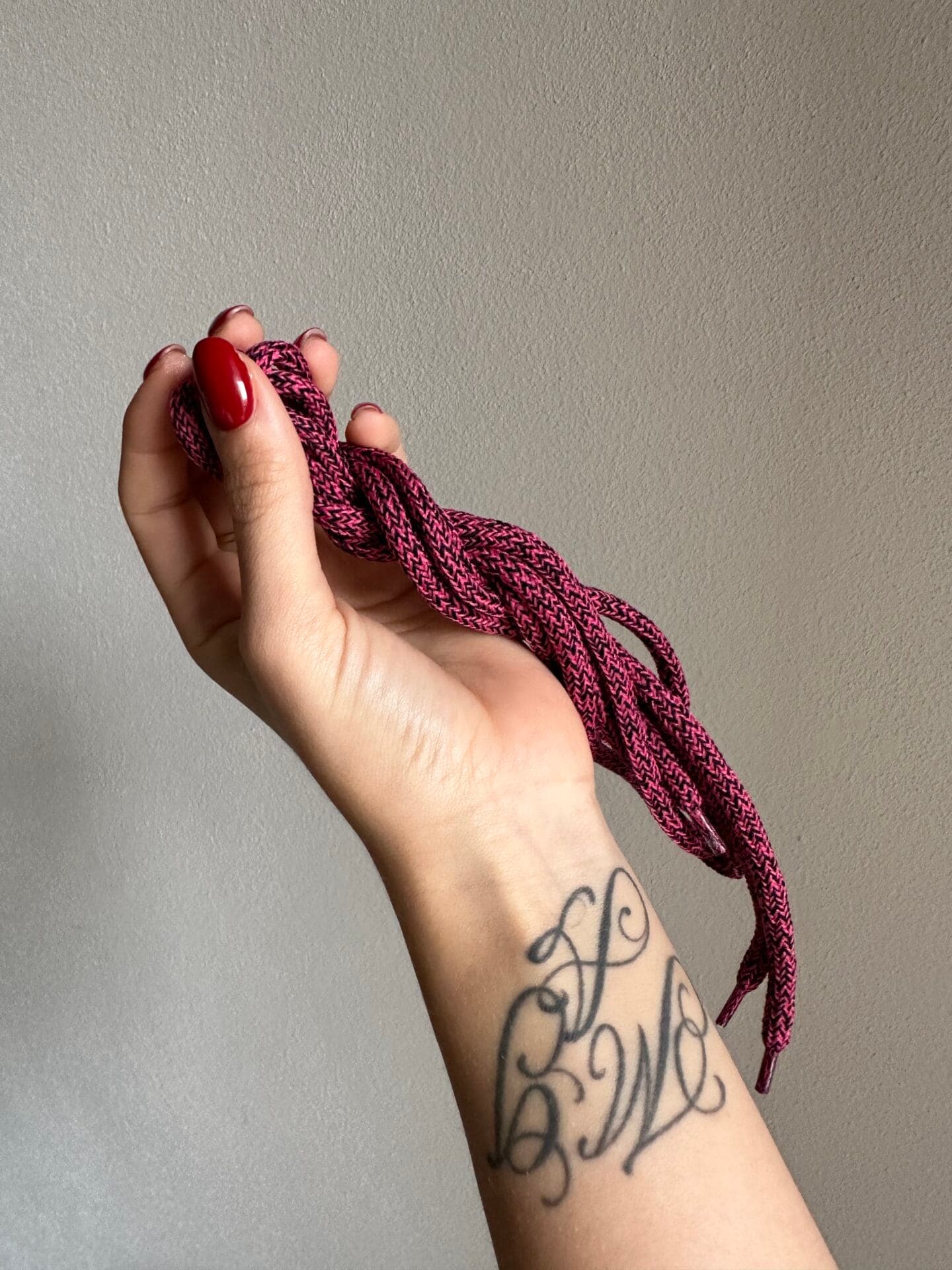 Lacci Yuool intrecciati in lana rosa tenuti in mano